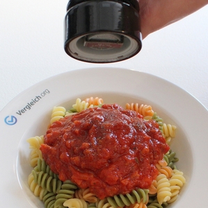 Portion Nudeln mit Tomatensoße auf einem Teller wird mit Pfeffer gewürzt