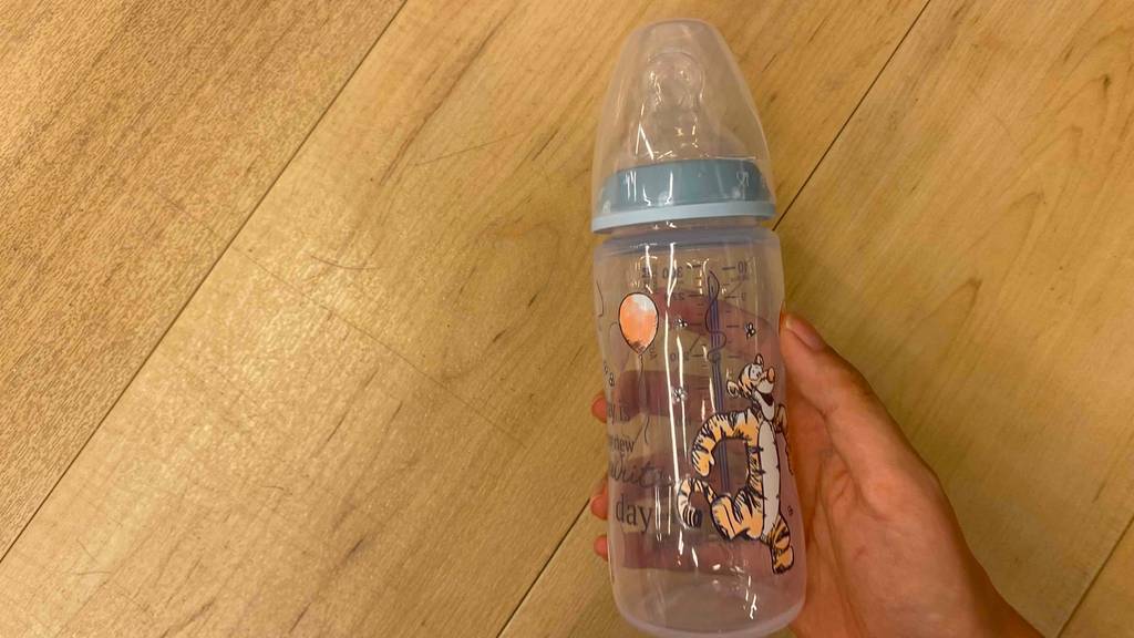 Hand hält eine ausgepackte Babyflasche