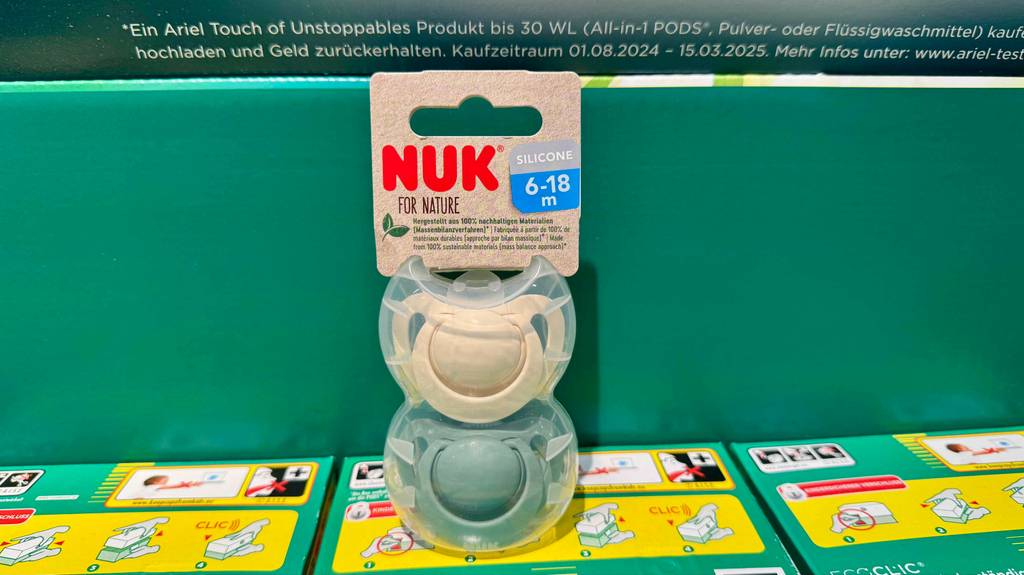 NUK-Schnuller-Test: Eine Verpackung mit zwei Schnullern steht auf einem Waschmittelkarton.
