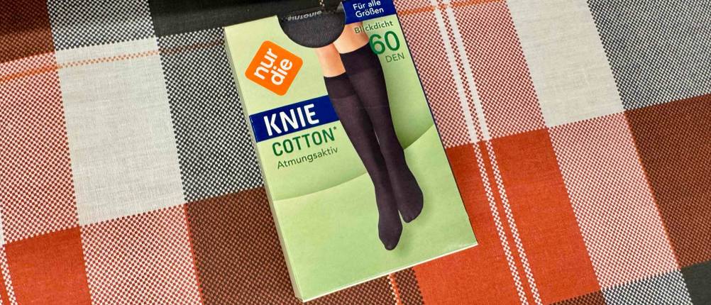 Kniestrümpfe-Test: Eine Verpackung mit Kniestrümpfen aus atmungsaktive Baumwolle liegt auf einem rot-schwarz karierten Stoff.