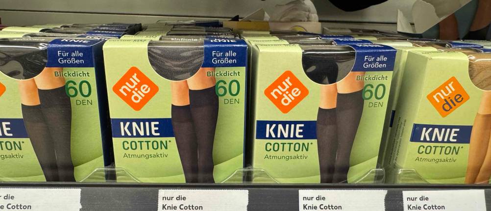 Kniestrümpfe im Test stehen innerhalb ihrer Verpackungen in einem Verkaufsregal.