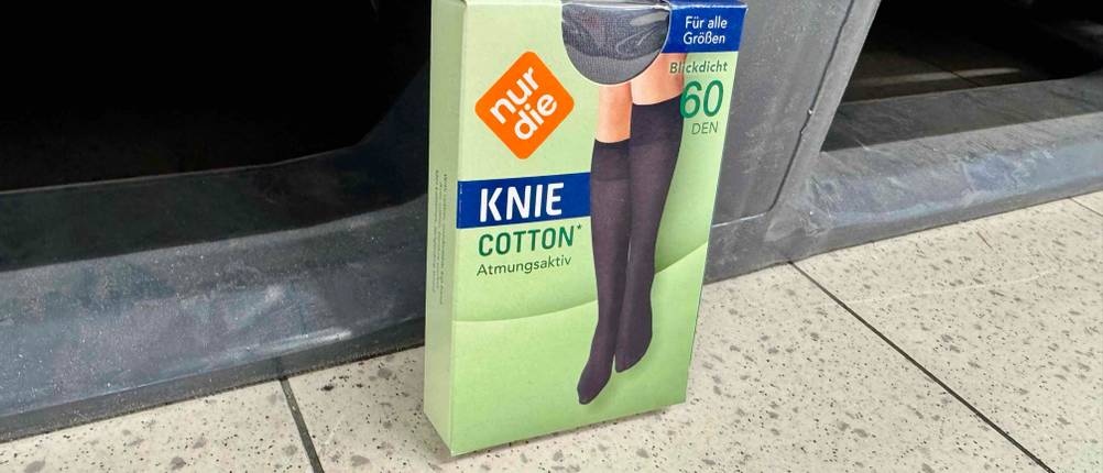 Kniestrümpfe-Test: Atmungsaktive Baumwoll-Kniestrümpfe in Verpackung lehnen an einem schwarzen Korb.