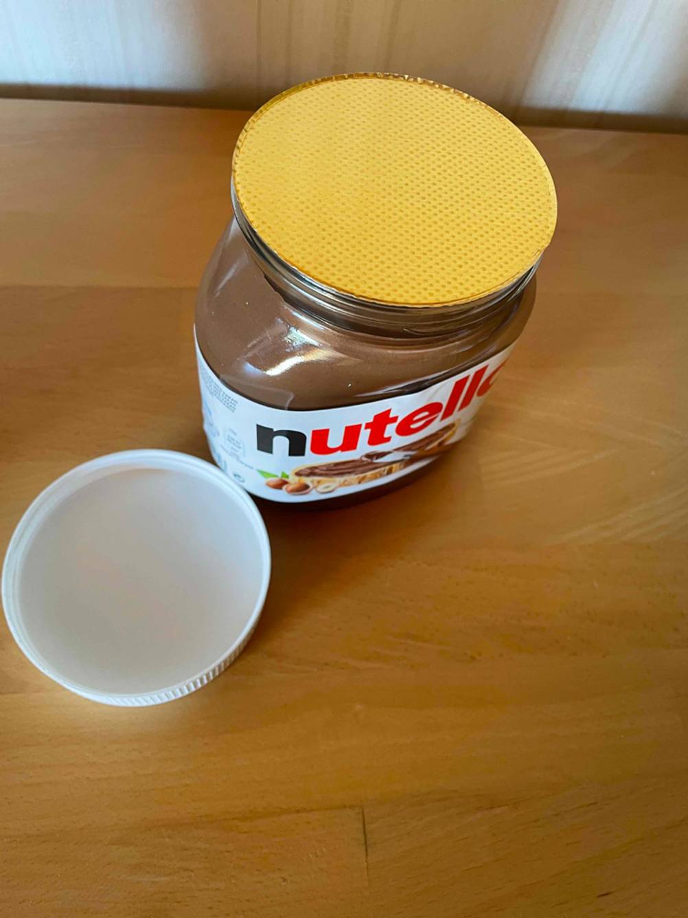 Eine getestete Nuss-Nougat-Creme befindet sich in einem versiegeltem Glas neben dem Deckel. 