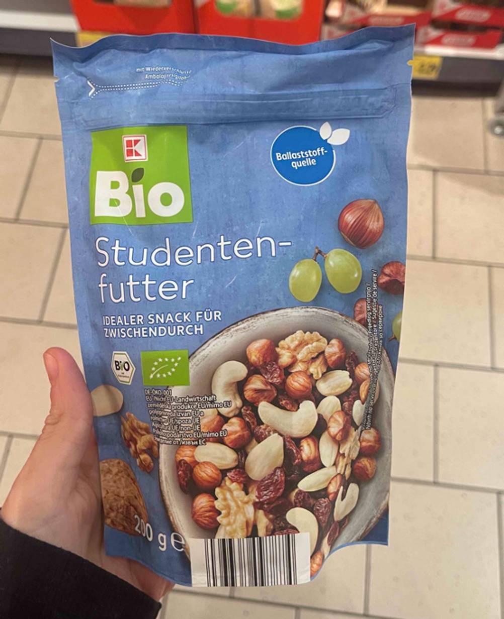 Eine Hand hält die blaue, wiederverschließbare 200-g-Tüte Studentenfutter, das sich aus der getesteten Nussmischung zusammensetzt.