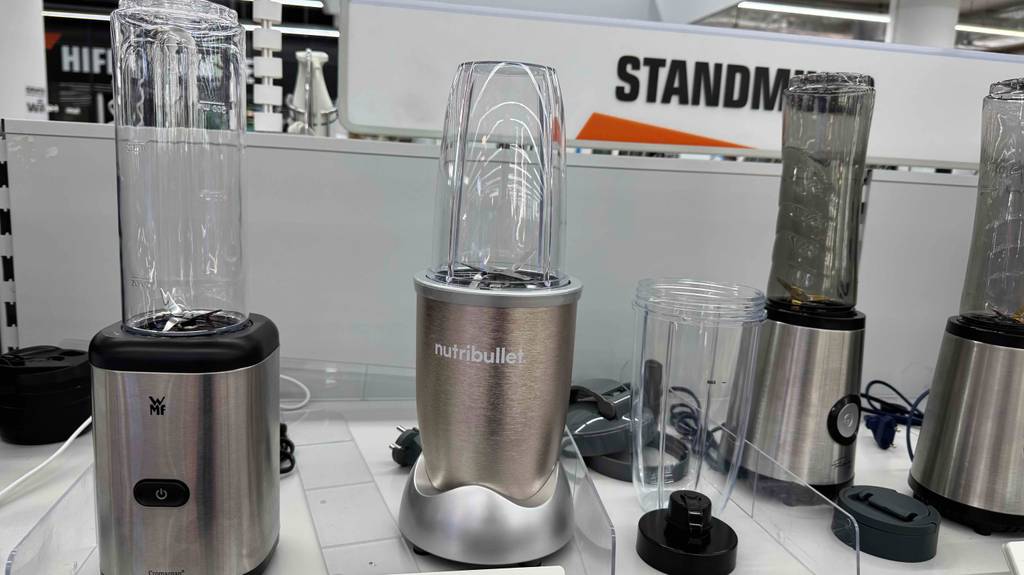 Frontansicht eines Nutribullet-Mixers, der zum testen zwischen anderen Geräten steht.
