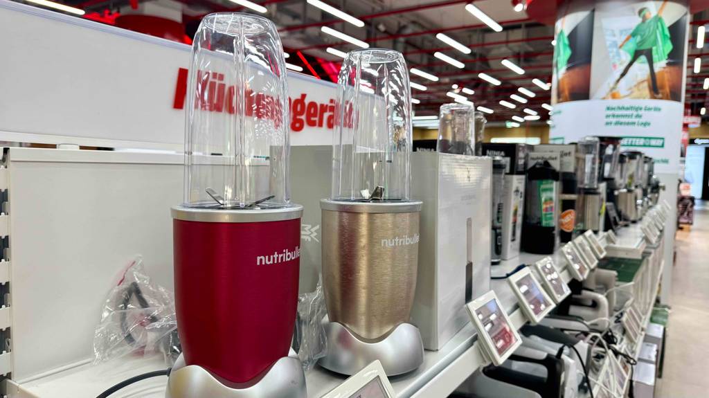 Nutribullet-Mixer im Test: Mehrere Geräte in unterschiedlichen Farben stehen nebeneinander auf einem Regal.