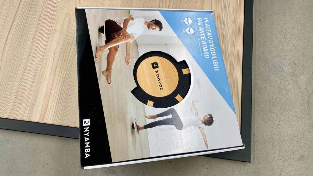 Balance-Board getestet: Ein originalverpacktes Board quer auf einem Holzboden.