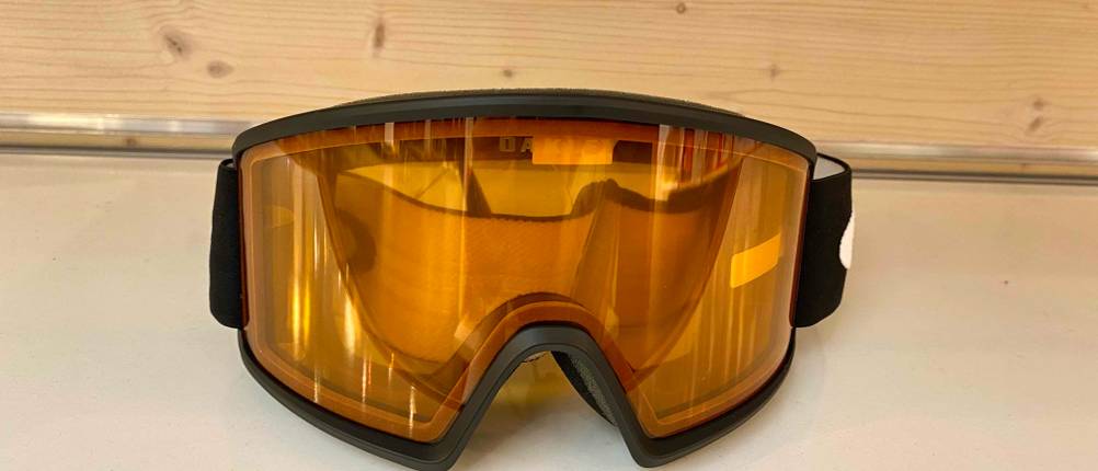 Skibrillen im Test: Skibrille mit großer oranger Sichtscheibe befindet sich vor einer hellen Holzfläche