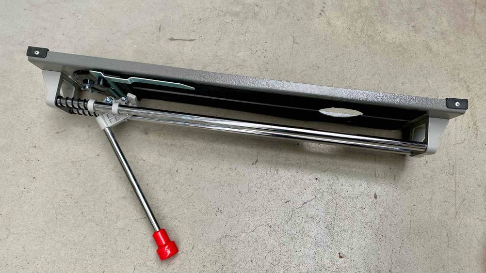 Fliesenschneider getestet: Ein Gerät auf der Seite liegend von oben auf einer grauen Fläche.