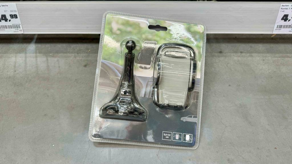 Handyhalterung fürs Auto im Test: eine in Kunststoff verpackte Handyhalterung lehnt vor einem Verkaufsregal