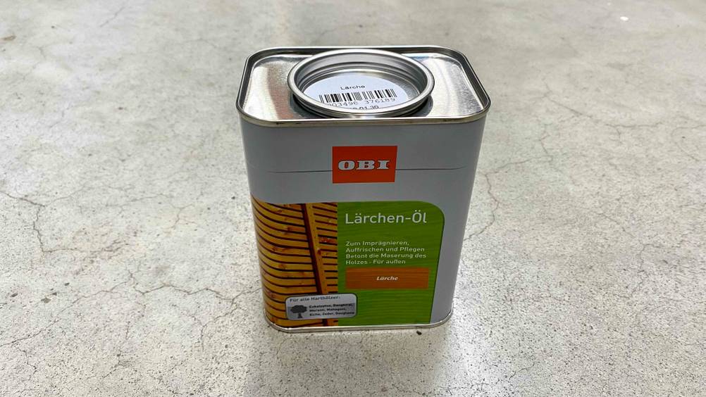 Ein Kanister Lärchenöl im Test von oben mit Sicht auf den Verschlussdeckel auf einer grauen Fläche stehend.