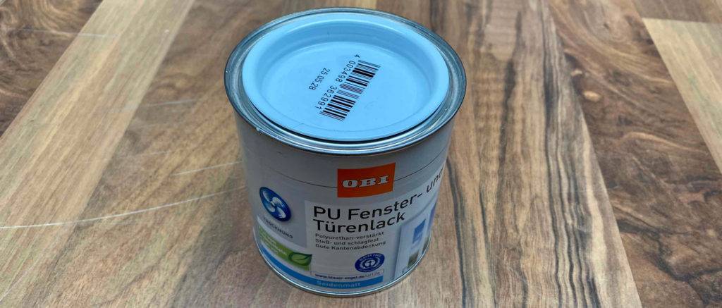 Der getestete Fenster- und Türenlack steht auf dem Boden.