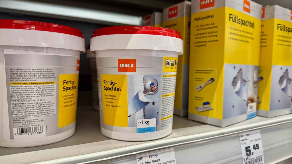 Getestet: Der Wandspachtel (innen) als Fertigmasse im 1-kg-Gebinde steht in einem Baumarkt auf einem Regal neben Füllspachtel-Packungen.