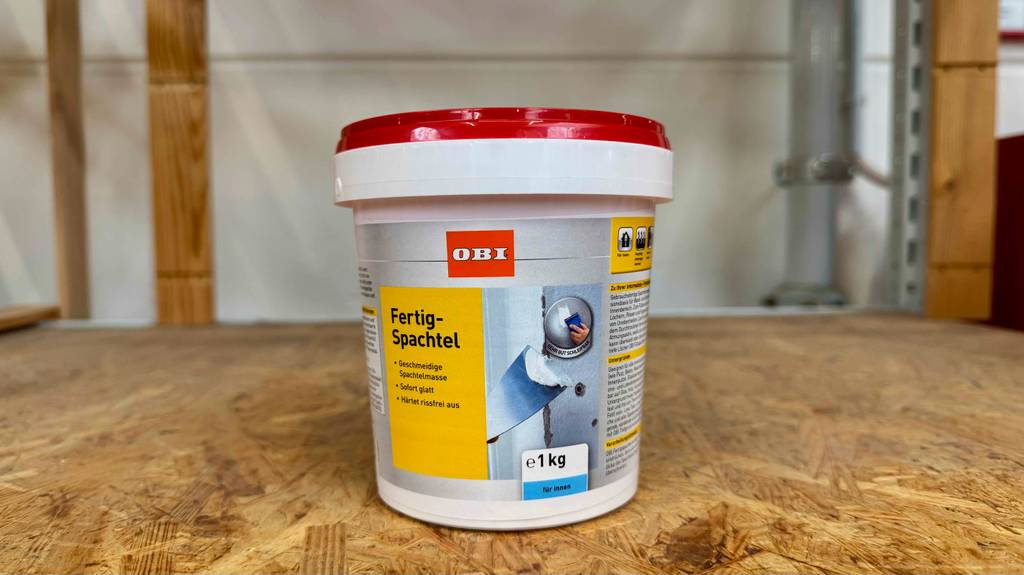 Der getestete Wandspachtel (innen) als Fertigmasse im 1-kg-Gebinde steht in einem Baumarkt.