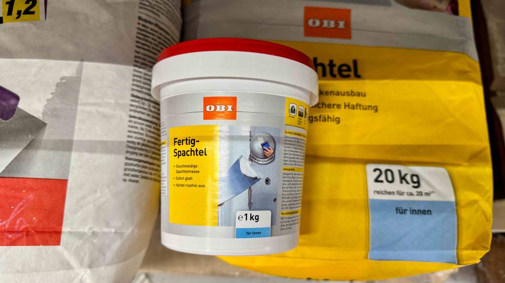 Im Test: Wandspachtel (innen) als Fertigmasse im 1-kg-Gebinde liegt auf einem 20-kg-Sack mit Pulver.