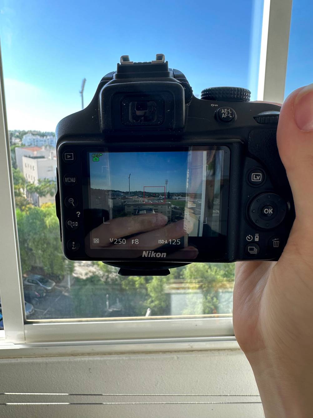 Objektiv für Nikon getestet: Eine Hand hält eine eine eingeschaltene Kamera vor ein Fenster.