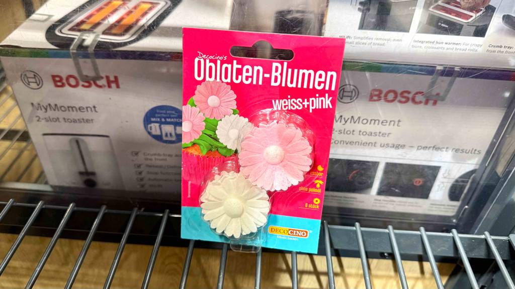 Die 6-Stück Oblaten-Blumen der Torten-Deko im Test lehnen an einer Zwei-Schlitz-Toaster-Verpackung.