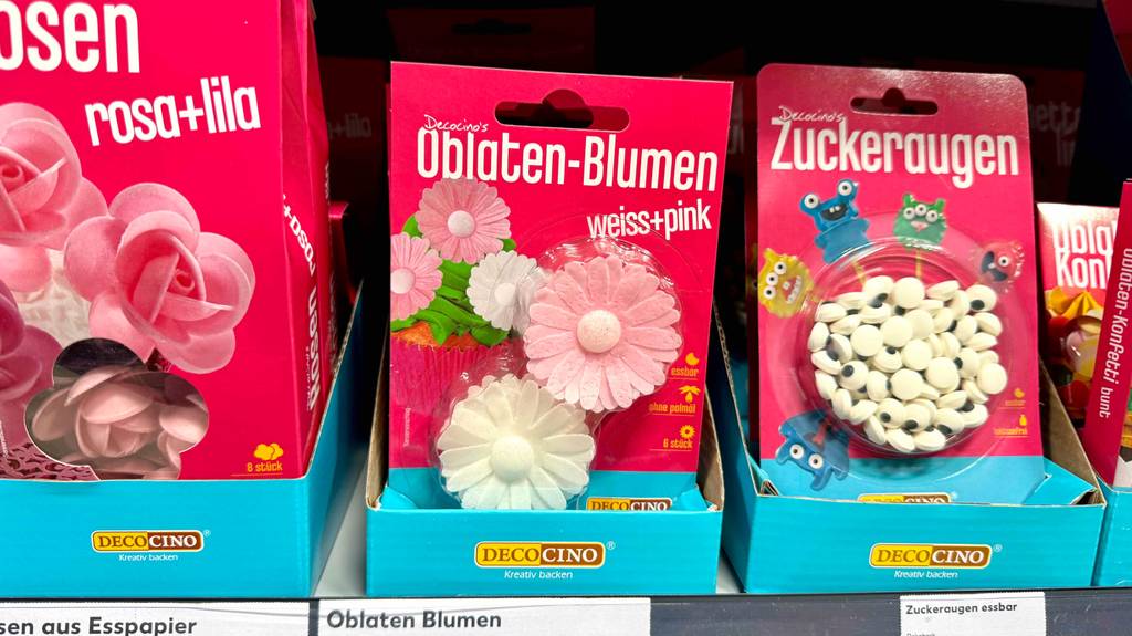 Die 6-Stück Oblaten-Blumen der getesteten Torten-Deko stehen in der Verpackung eingeschweißt im Verkaufsregal neben weiteren Kuchen-Dekorationen.