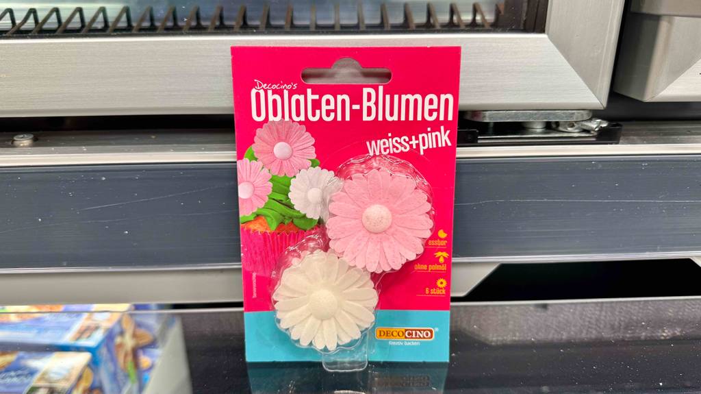 Die 6-Stück Oblaten-Blumen der Torten-Deko im Test befinden sich in der Verpackung eingeschweißt im Verkaufsregal.