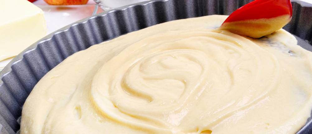 Obstkuchenformen im Test: Teig wird mit einem Kunststoffschaber in einer Kuchenform verteilt.