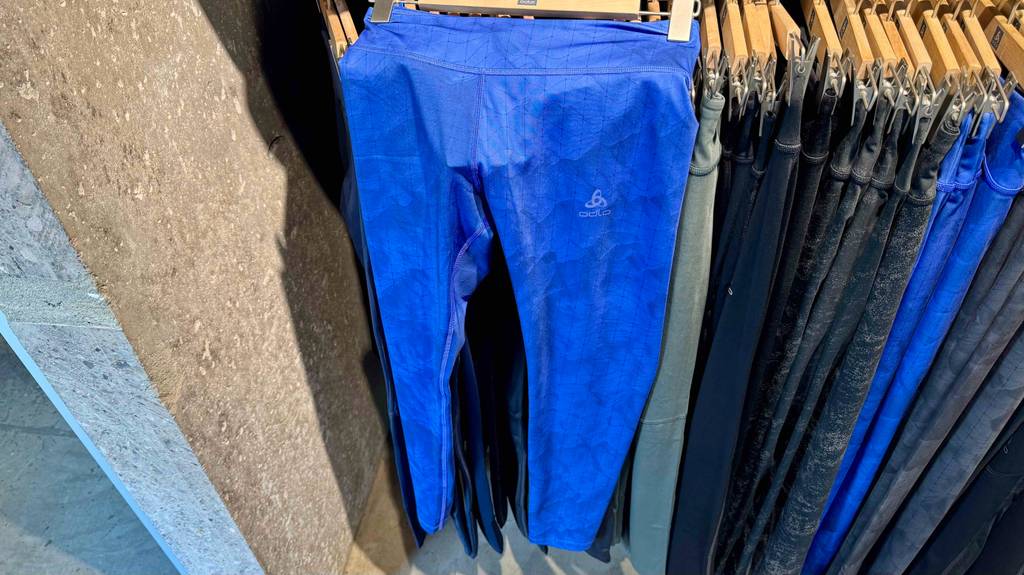Im Test: Die Damen-Langlaufhose in leuchtendem Blau hängt an einem Bügel über weiteren Hosen in einem Sportbekleidungsladen.