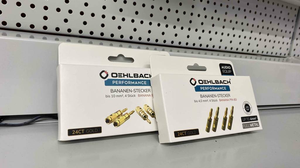 Bananenstecker-Test: zwei weiße Packungen mit Performance Bananen-Stecker von Oehlbach stehen in einem Verkaufsbereich.