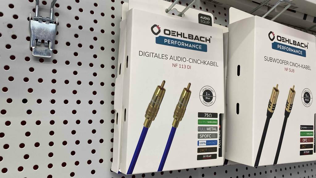 zwei Verpackungen in Weiß inklusive Oehlbach-Cinch-Kabel im Test, versehen mit goldenen Steckern, hängen an einem Verkaufsstand.