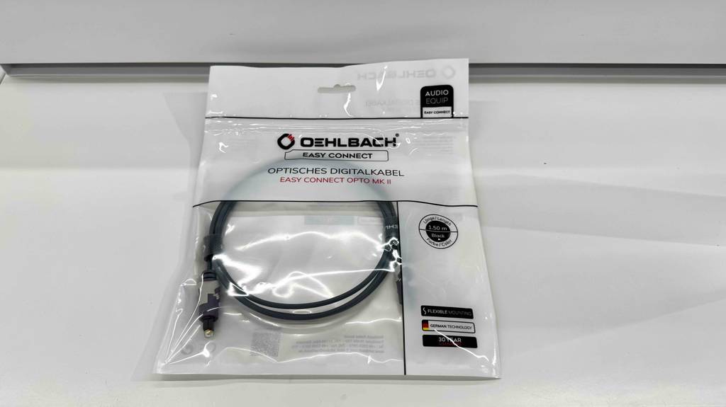 Ein getestetes optisches Kabel liegt in seiner Kunststoffverpackung auf einer weißen Oberfläche.