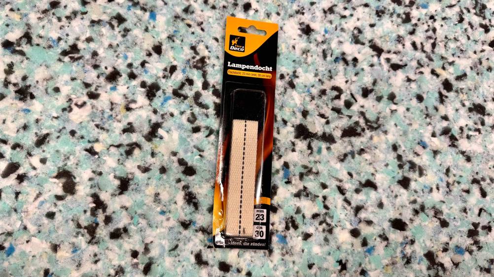 Auf einer bunten Fläche liegt eine Packung des Öllampendochtes im Test.