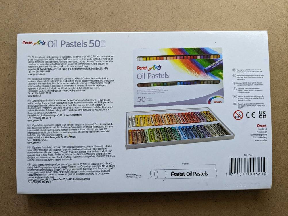 Rückseite einer Verpackung der getesteten Ölpastellkreide mit Informationen auf einer Holzfläche.