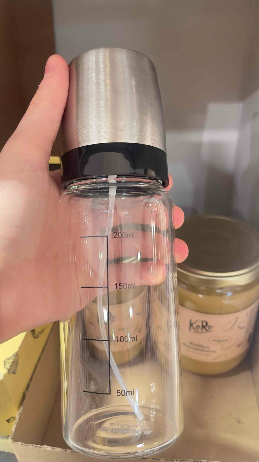 Ölsprüher-Test: Eine Hand hält die Flasche mit der Scala nach vorne.