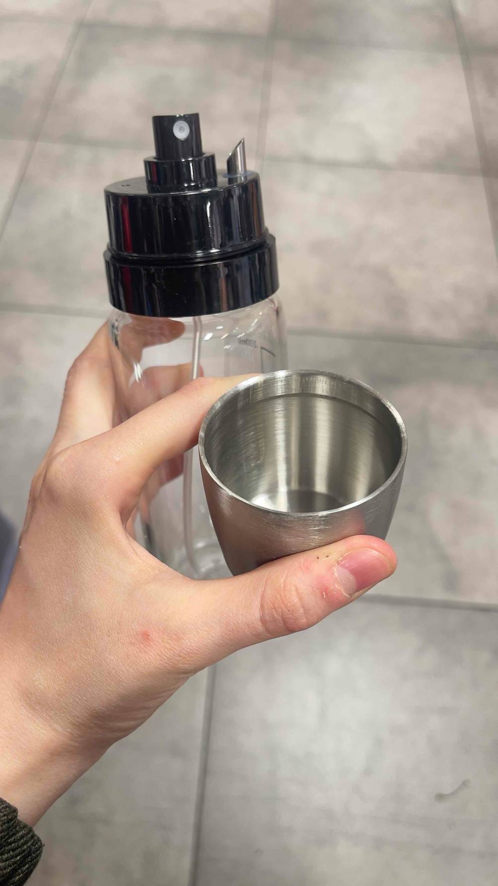 Eine Hand hält den Ölsprüher im Test und dessen Deckel.