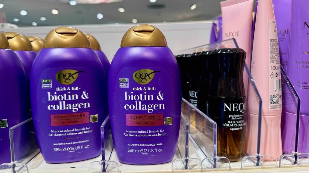Im Test: Collagen-Shampoo in violettfarbenen Flaschen steht neben anderen Haarpflegeprodukten auf einem Regal im Drogeriemarkt.