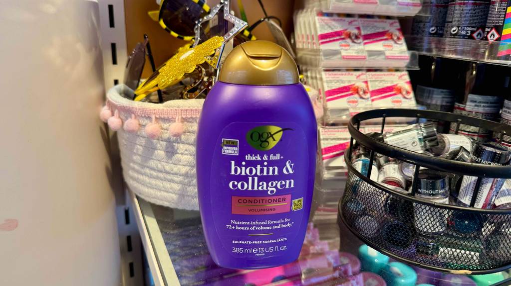 Eine violettfarbene Flasche mit Collagen-Shampoo im Test steht vor mverschiedenen kosmetischen Produkten.
