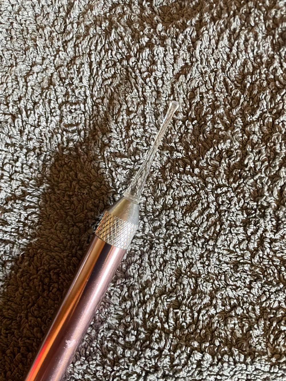 Nahaufnahme eines Ohrenschmalz-Entferners im Test auf einem grauen Handtuch.