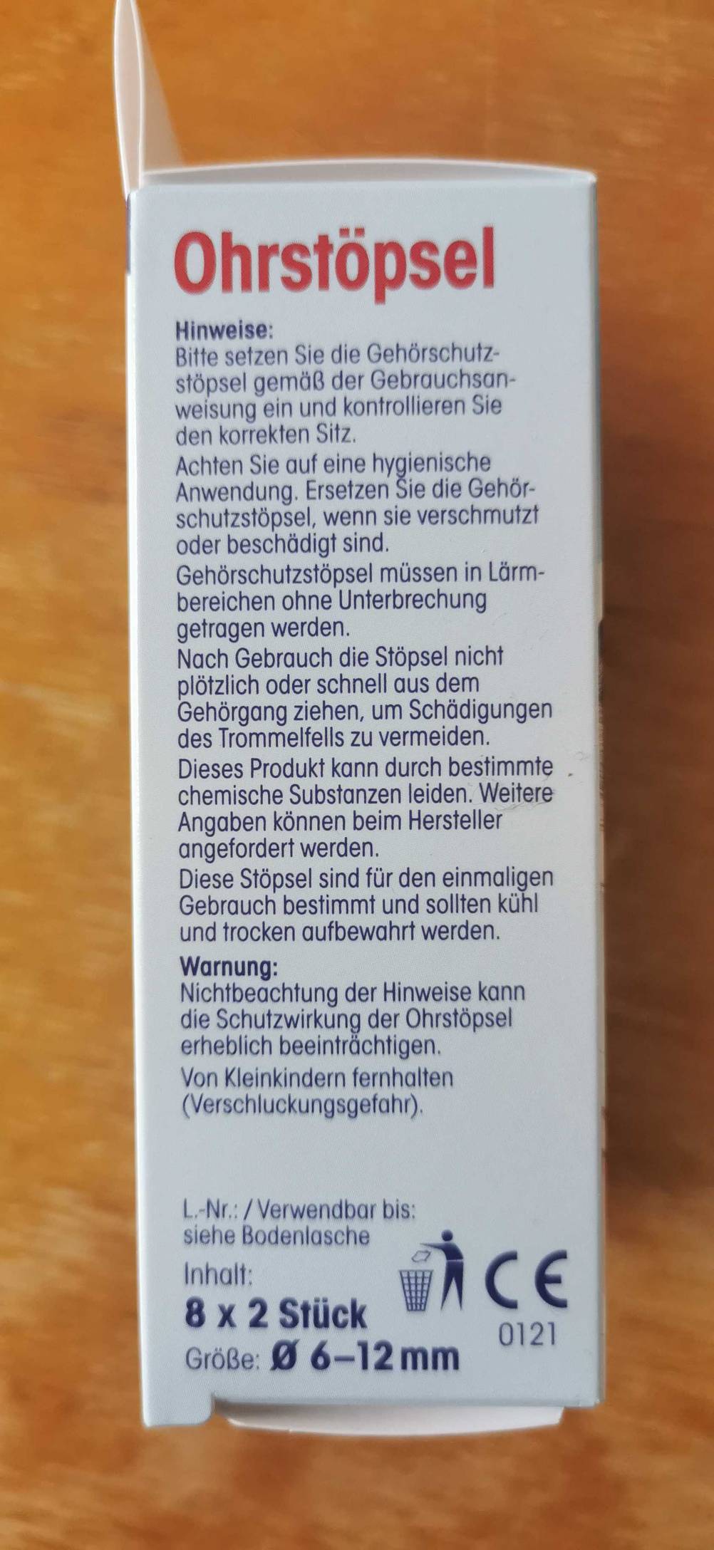 Seitenansicht einer Packung der Ohrstöpsel zum Schlafen mit Informationen auf einer Holzfläche.