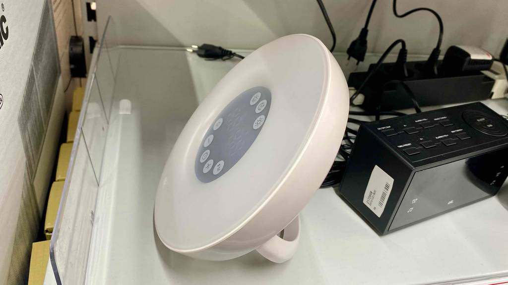 Ein runder, weißer Lichtwecker steht zum Test bereit in einem Verkaufsregal mit einem anderen Modell in Schwarz.