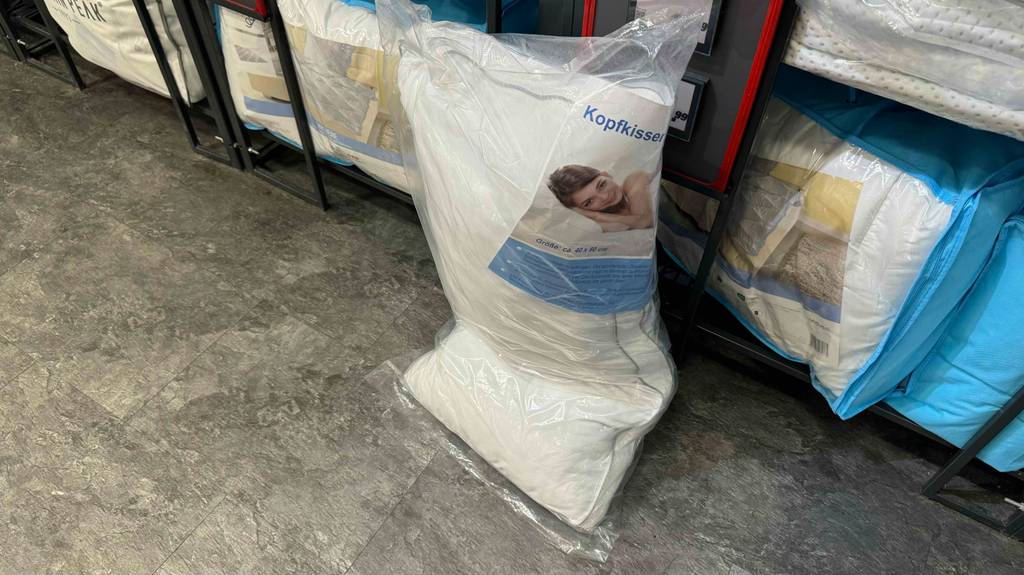 Getestet: Kühlende Kopfkissen in einem Geschäft; ein Modell in Weiß steht eingeknickt vor einem Verkaufsregal auf dem Boden.