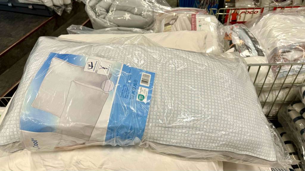 Im Test: ein kühlendes Kopfkissen liegt in der originalen Kunststoffverpackung auf einem Stapel Kissen im Verkaufsbereich.