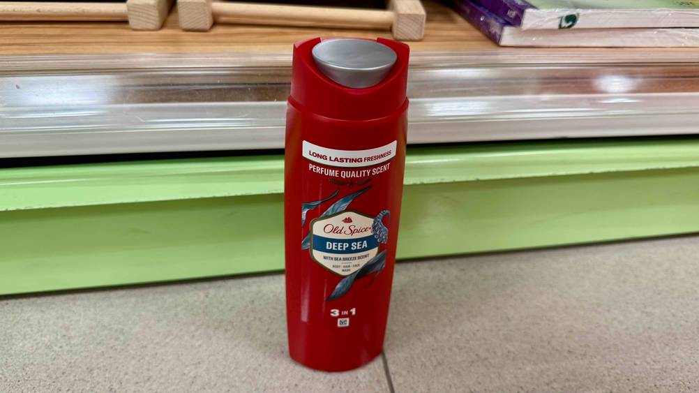 Eine Flasche des getesteten Old-Spice-Duschgels vor einem Regal auf dem Boden stehend.