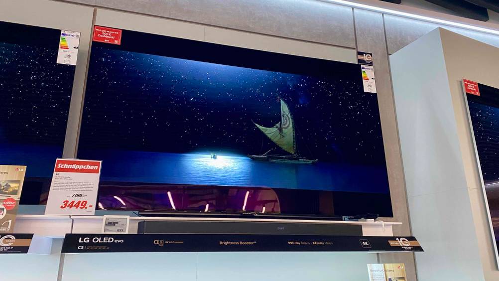 Ein getesteter OLED-TV von schräg unten in einer Verkaufsfläche mit Preisangaben.