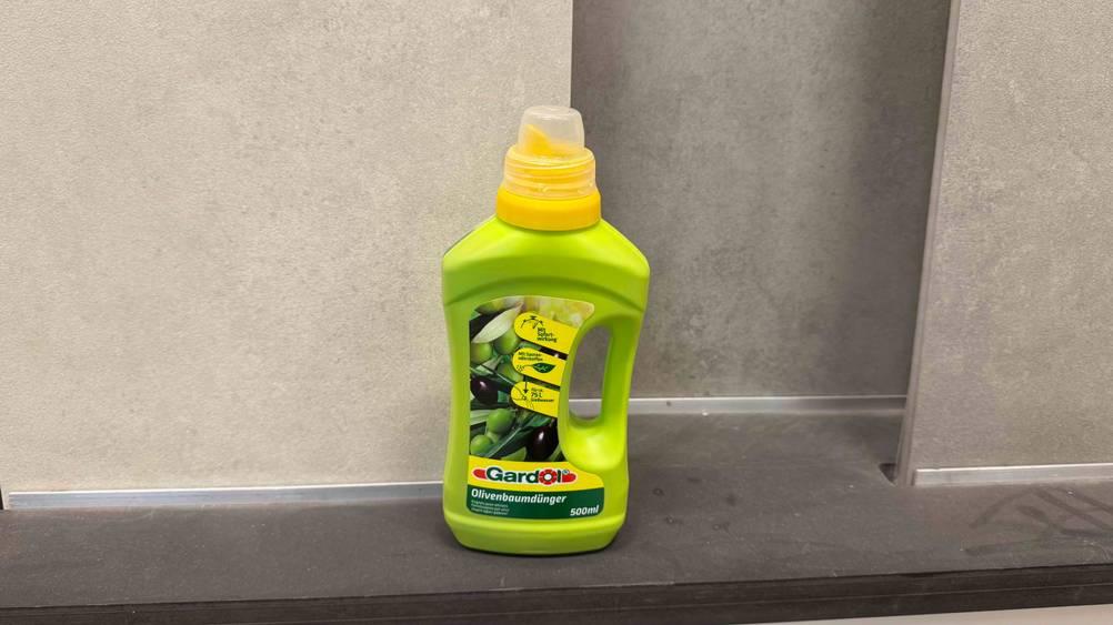 Der getestete Olivenbaum-Dünger vor einer grauen Wand.