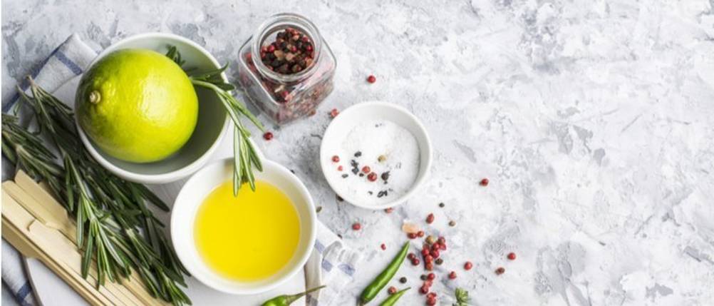Bertolli-Olivenöl getestet: Auf einer hellen Küchenfläche stehen kleine Schälchen mit Salz, Olivenöl, Zitrone und diversen Gewürzen. 