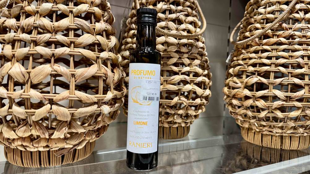 Getestet: Ein Olivenöl mit Zitrone vor drei Körben auf einer Glasplatte.