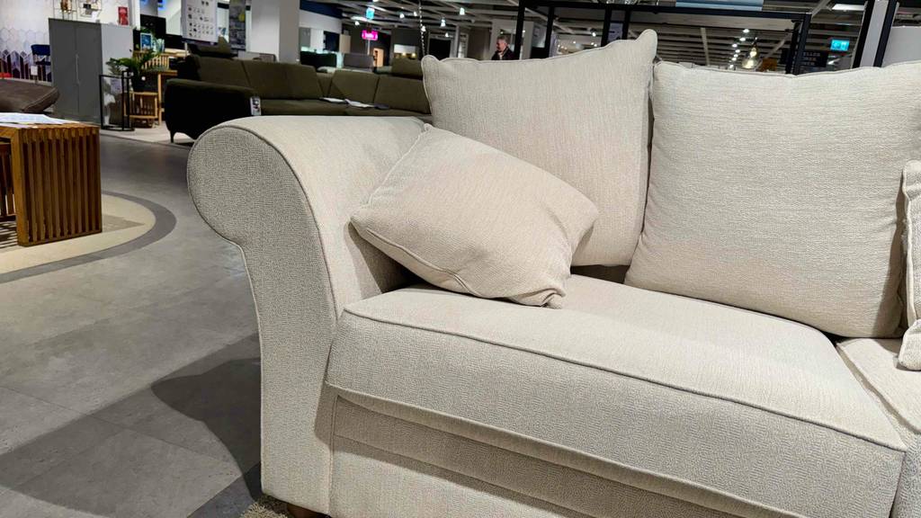 Detailansicht eines getesteten 3-Sitzer Sofas mit hellem Stoffbezug und Kissen.