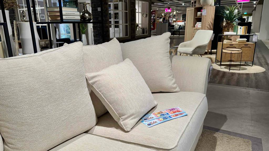 Ein 3-Sitzer Sofa im Test, das mit einem hellen Bezug ausgestattet ist, steht inmitten eines Möbelhauses.
