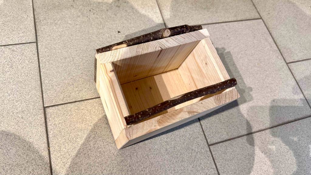 Blick von oben auf ein am Boden liegendes getestetes Vogelhaus aus Holz.