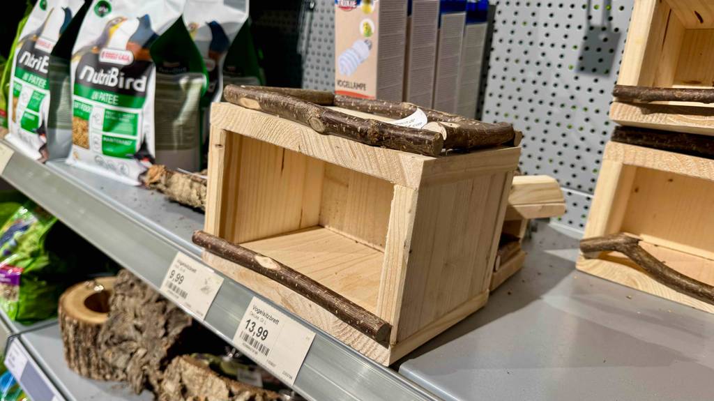 Im Test: Blick von schräg vorn auf ein Vogelhaus aus Holz, das in einem Verkaufsregal steht.