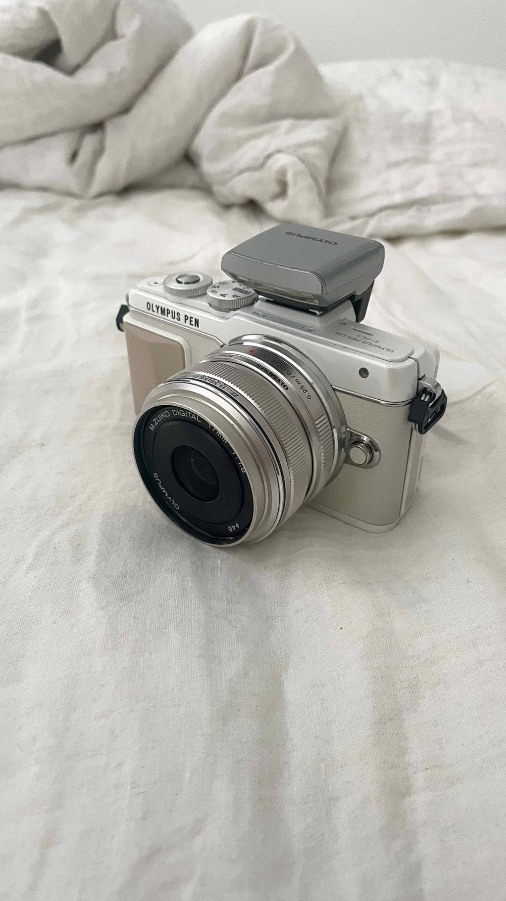 Systemkamera-Test: ein weißes Modell der Marke Olympus steht auf einer weißen Bettdecke.