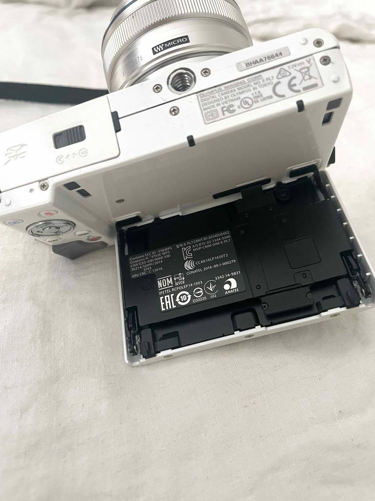 Systemkameras im Test: ein weißes Olympus-Modell mit geöffnetem LCD-Bildschirm auf einer weißen Oberfläche.